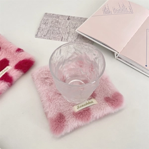 Close-up of pink plush heart coaster with hammer textured glass on desk
