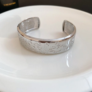 Detailed macro view of silver oval cuff bracelet featuring vintage embossed abstract patterns