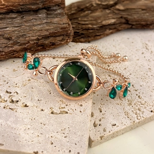 Detail of rose gold watch band with green gemstones and adjustable sliding clasp closure