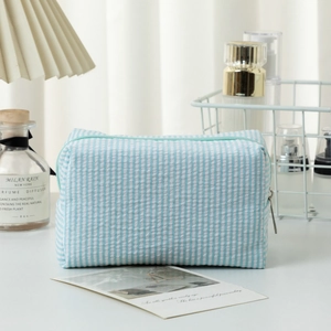 Macro detail of seersucker makeup bag with blue stripes and mint green zipper closure