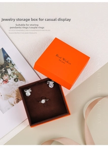 Detail of orange jewelry box with bow earrings and ring on velvet lining