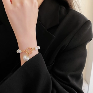 Dettaglio del bracciale di perle con chiusura OT dorata e ciondolo a cuore di diamanti
