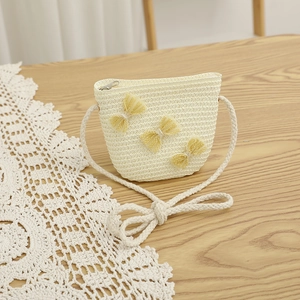 Detail of cream straw bag for kids with yellow lace bows and cotton rope strap
