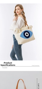 Detail of embroidered evil eye tote bag with tassel trim and brown leather handles
