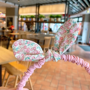 Close-up of pink pleated fabric headband for girls with cute cherry pattern bow detail