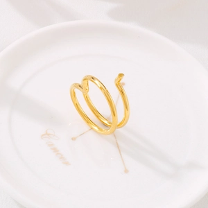 Minimalist gold coiled ring displayed on a white ceramic plate with Cancer zodiac text
