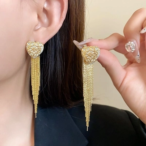 Detail of gold-plated long tassel earrings with sparkling heart-shaped studs on model