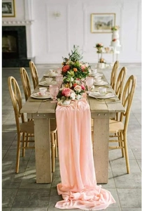 Pink chiffon table runner draped elegantly on a wooden table for wedding decor