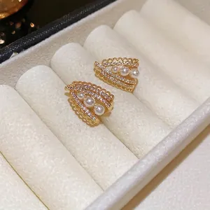 Lace V-shaped gold earrings with sparkling zircons and gradient pearls on velvet