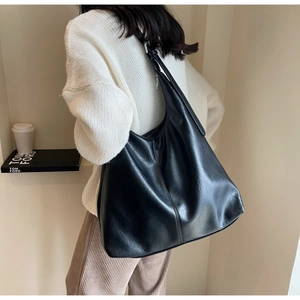 Side view of a large black soft leather hobo bag worn by a model for a casual look