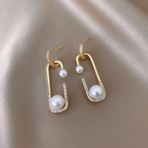 Detail of gold twisted earring with champagne imitation pearl and micro-inlaid zircons
