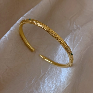 Vintage golden open cuff bracelet with textured finish and two green gemstone accents