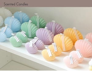 Detailed close-up of shell-shaped scented candles in pastel colors on a white shelf