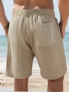 Detail of men's beige knitted stripe shorts featuring elastic waist and back pocket