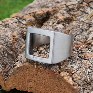 Gros plan de la bague en métal brossé argenté avec découpe carrée sur écorce d'arbre