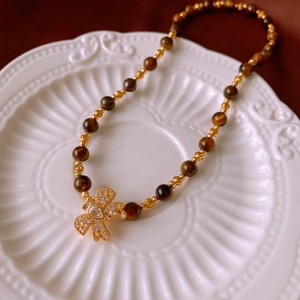 Macro view of tiger eye bead necklace with bow-shaped cubic zirconia pendant on white tray