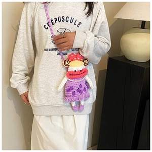 Detail of handmade crochet girl-shaped crossbody bag with pearl accents and purple strap