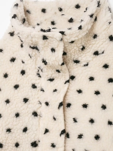 Détail de la texture polaire douce à pois noirs et col montant de la veste