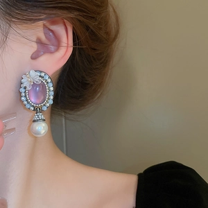 Detail of vintage resin butterfly earring with purple oval stone and pearl on a model
