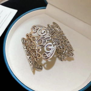 Detailed close-up of a vintage silver-finish open bangle with intricate floral hollow patterns