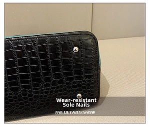 Detail of black crocodile texture leather bag bottom with silver protective metal studs