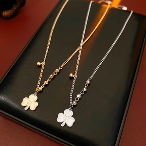 Detailed close-up of clover pendant necklaces in gold and silver beaded chains