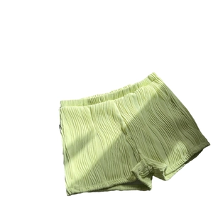 Lime green pleated high-waisted shorts with elastic waistband and lettuce edge hem