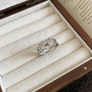 Detailed close-up of a silver triple-star ring with zircon accents in a wooden jewelry box
