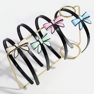 Detail of four black plastic headbands with colorful cream-style bows on a gold rack