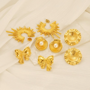 Vue détaillée de quatre boucles d'oreilles en acier doré avec perles et motifs papillon