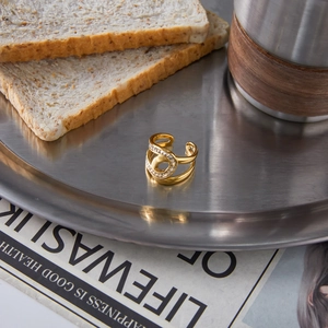 Détail d'une bague multicouche en acier inoxydable doré 18 carats sur un fond de style