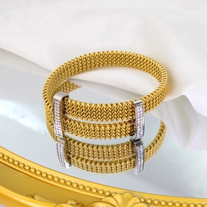 Golden mesh stainless steel bracelet with zircon inlay on a reflective surface