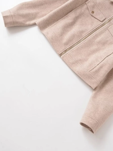 Detail of beige fleece jacket showing golden buttons, flap pocket and smooth zipper