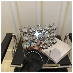 Detail der silbernen Metallic-Kugel-Clutch mit dekorativen Perlen und Kettenriemen