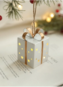 Détail boîte cadeau de Noël en fer blanc avec nœud doré et lumière LED chaleureuse