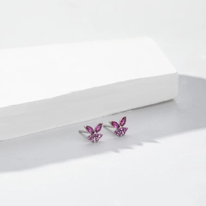 Elegant silver butterfly stud earrings with pink purple zircon on a minimalist background