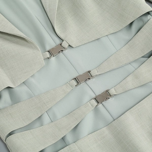 Détail d'une robe vert clair avec boucles métalliques argentées et tissu texturé