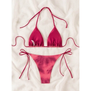 Flat lay of pink lace-up bikini set with marble tie-dye pattern on white fabric