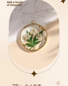 Detail view of handmade golden pendant with white dried flowers and gold leaf resin inlay