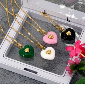 Detail of four colorful heart pendant necklaces in a white jewelry box with flowers