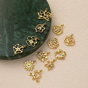 Détail de pendentifs floraux en acier doré ornés de zircons colorés sur marbre