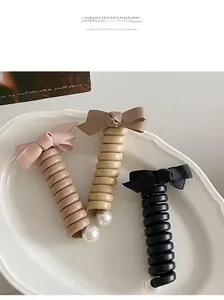 Détail d'élastiques spirales avec nœuds et perles en rose, beige et noir élégants