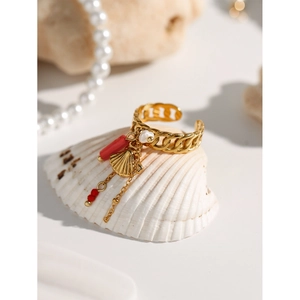 Detail of gold seashell ring with red beads and white pearl charms on natural shell
