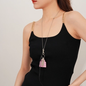 Détail macro du collier chaîne à billes argentées avec pendentif sac à main rose serti