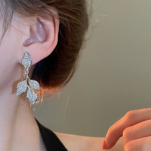 Macro shot of silver leaf tassel earrings with sparkling zircon crystals on model