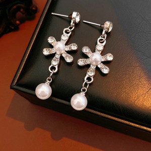 Detail view of silver floral earrings with sparkling crystals and hanging pearls