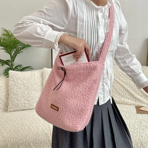 Detalle del bolso bandolera rosa de felpa con parche de logo en cuero y cordón decorativo