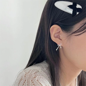 Detail of model wearing silver bow stud earrings and a black bow velvet hair clip
