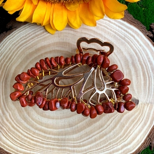 Detailed macro view of butterfly hair claw with golden metal and red crystal stones