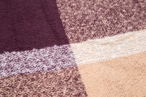 Close-up of soft plaid fabric texture in deep purple and beige tones for scarves
